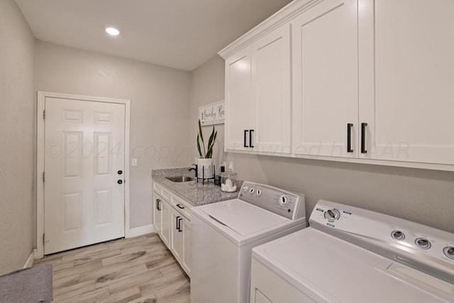 laundry area featuring cabinets, separate washer and dryer, sink, and light wood-type flooring