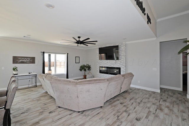 living room featuring ceiling fan, a fireplace, crown molding, and light hardwood / wood-style floors