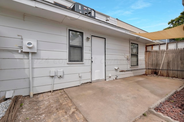 view of exterior entry with fence and a patio