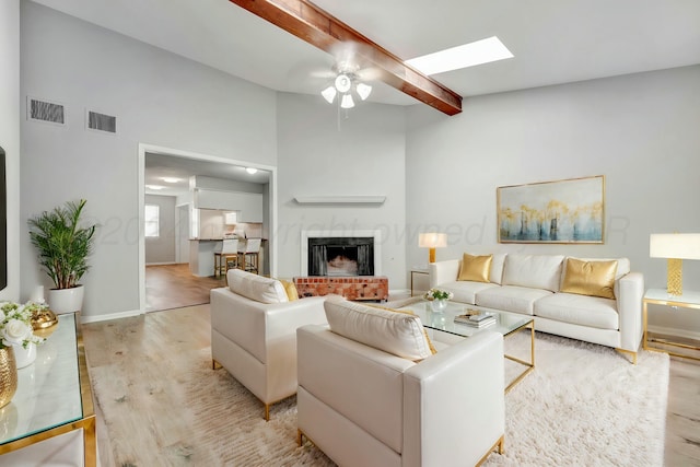 living area featuring baseboards, a fireplace, visible vents, and light wood-style floors