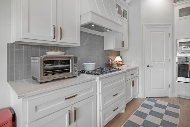 8100 Pensacola Ave, Amarillo, TX 79118 - kitchen featuring stainless steel appliances, tasteful backsplash, premium range hood, and white cabinetry