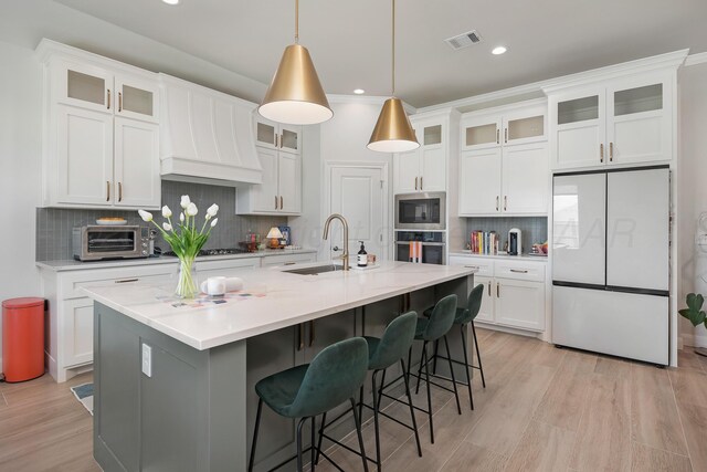 8100 Pensacola Ave, Amarillo, TX 79118 - kitchen featuring appliances with stainless steel finishes, decorative backsplash, white cabinets, a kitchen island with sink, and recessed lighting