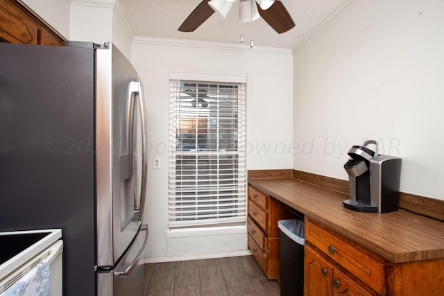 kitchen with ornamental molding, hardwood / wood-style floors, stainless steel fridge, and a textured ceiling