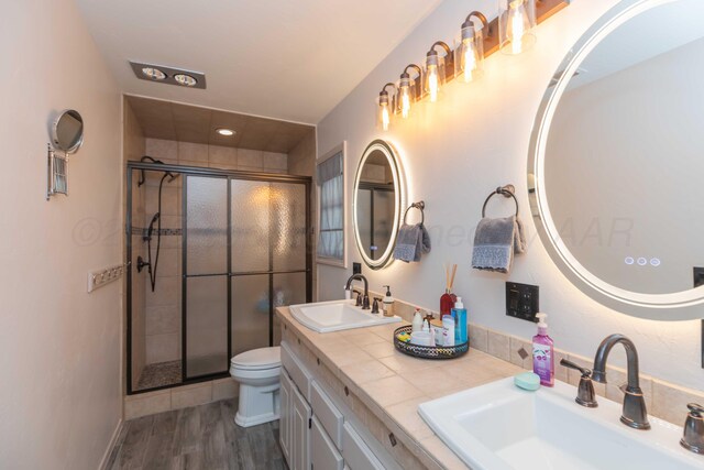 bathroom featuring toilet, an enclosed shower, vanity, and wood-type flooring