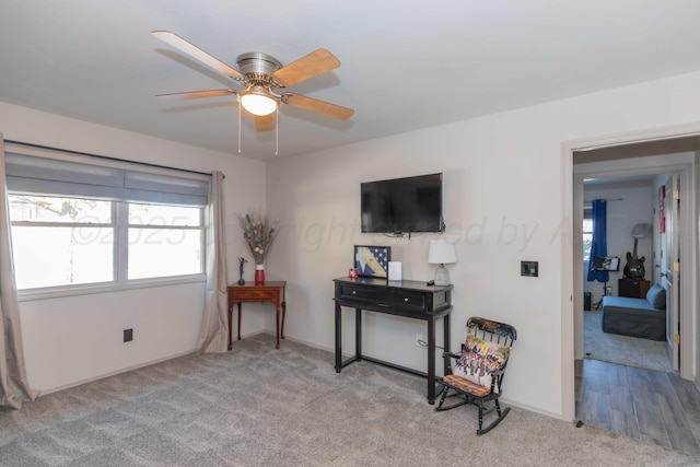 living area featuring light carpet, ceiling fan, and a healthy amount of sunlight