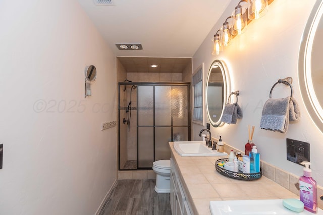 bathroom featuring hardwood / wood-style flooring, vanity, a shower with shower door, and toilet