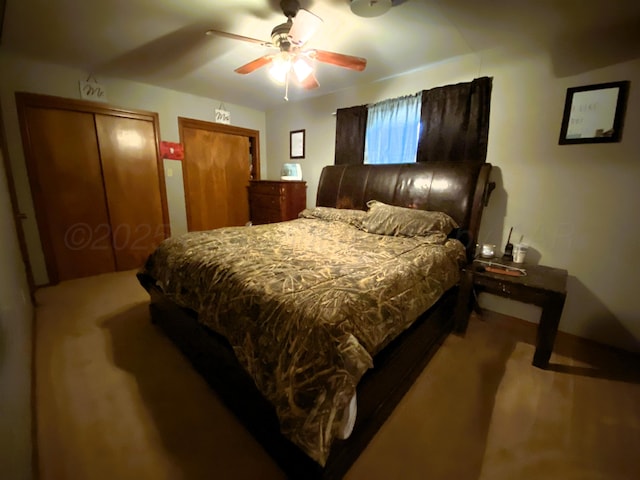 bedroom with ceiling fan, carpet floors, and two closets