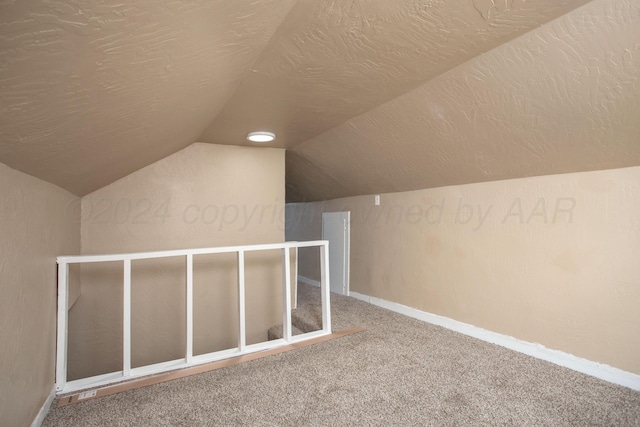 additional living space featuring carpet floors, vaulted ceiling, and a textured ceiling