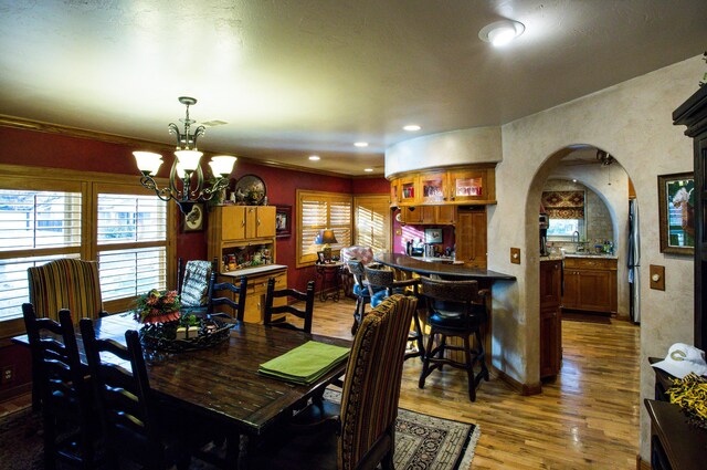 dining area with wood-type flooring, ornamental molding, and a notable chandelier