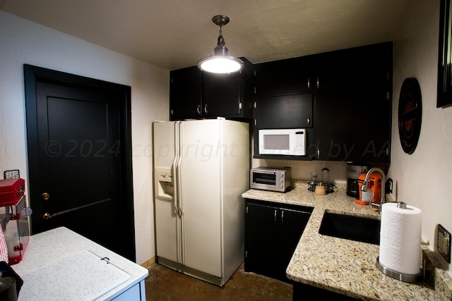 kitchen featuring decorative light fixtures, sink, white appliances, and light stone countertops