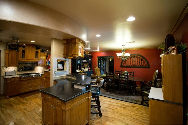 kitchen with a kitchen breakfast bar, ceiling fan with notable chandelier, light wood-type flooring, and a center island