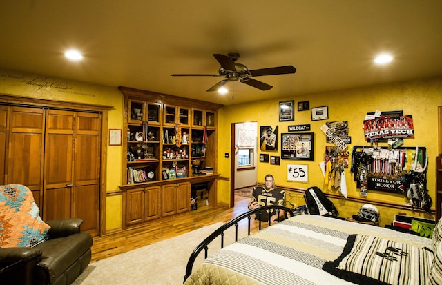 bedroom with light hardwood / wood-style floors, ceiling fan, and a closet