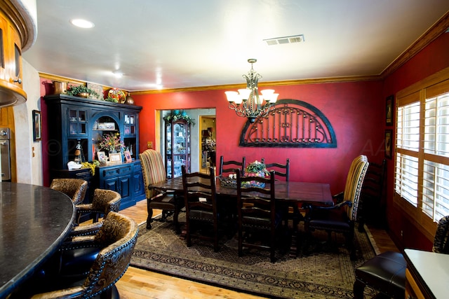 dining space with an inviting chandelier, crown molding, and light hardwood / wood-style flooring