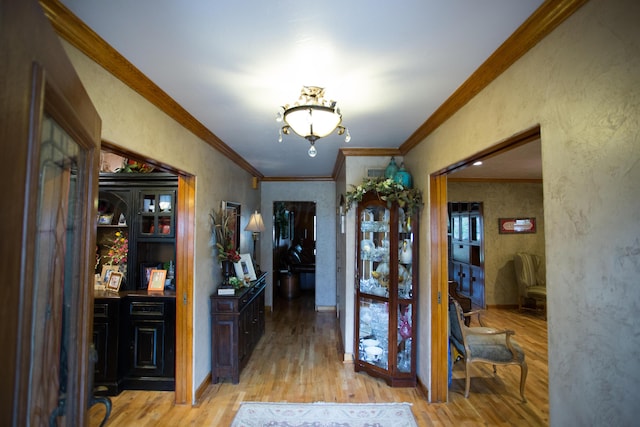 hallway with light wood-type flooring and ornamental molding