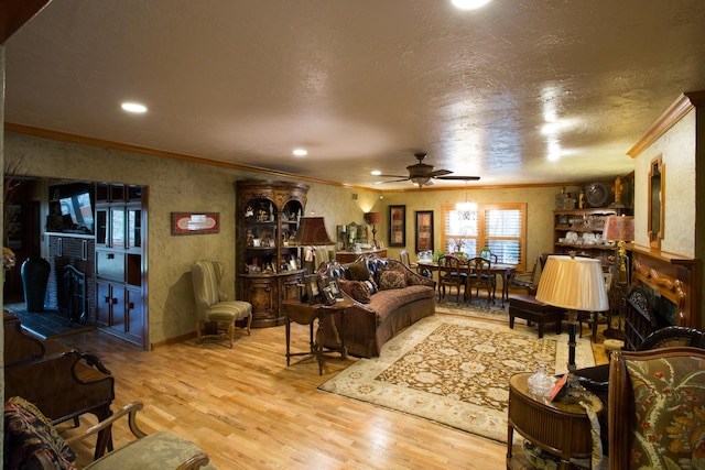 living room with a textured ceiling, crown molding, ceiling fan, and light hardwood / wood-style flooring