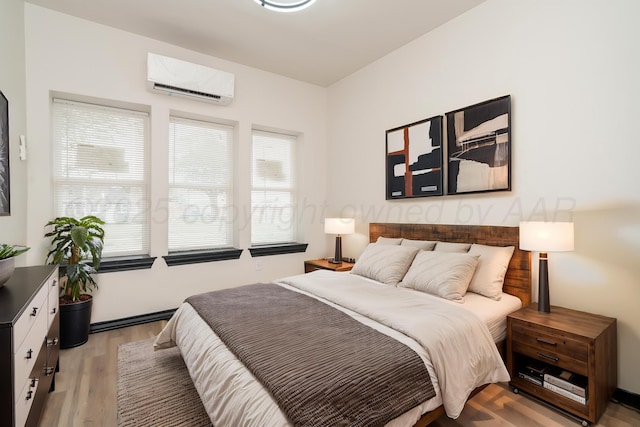 bedroom with an AC wall unit and light wood-style floors