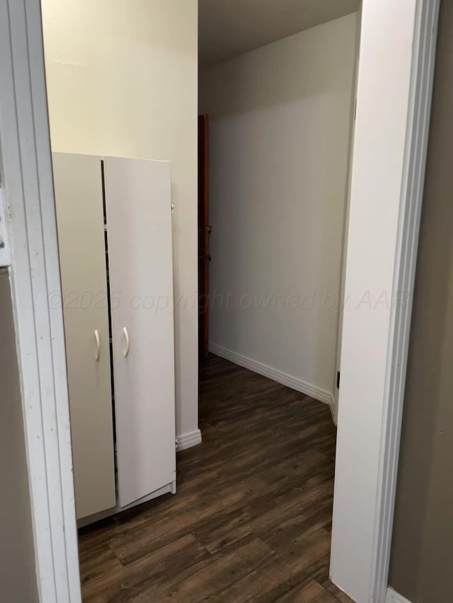 corridor with baseboards and dark wood-style floors