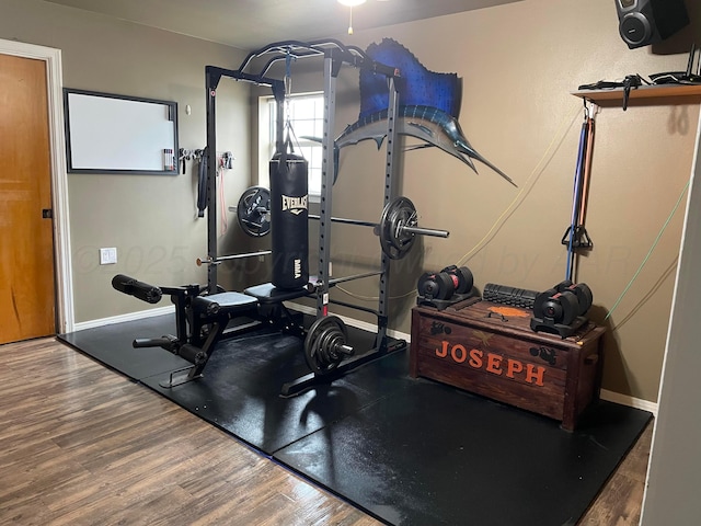 workout area with baseboards and wood finished floors