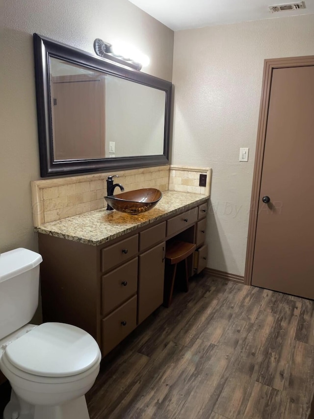 bathroom with toilet, tasteful backsplash, wood finished floors, and vanity