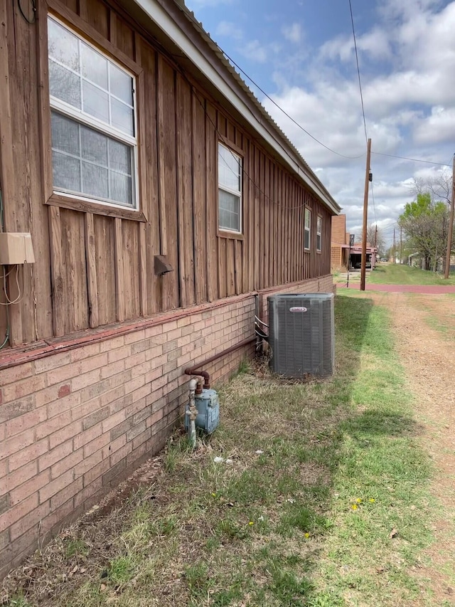 view of home's exterior with central AC, a lawn, and board and batten siding