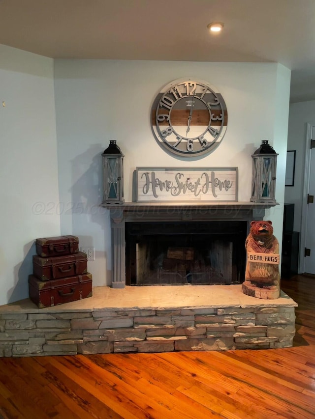 room details with recessed lighting, a fireplace with raised hearth, and wood finished floors