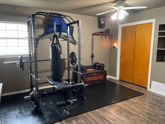 exercise area featuring visible vents, baseboards, a ceiling fan, and wood finished floors