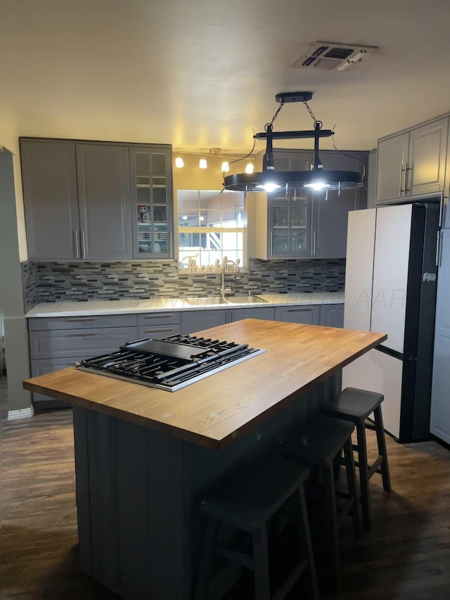kitchen with a sink, gray cabinets, freestanding refrigerator, and wood counters