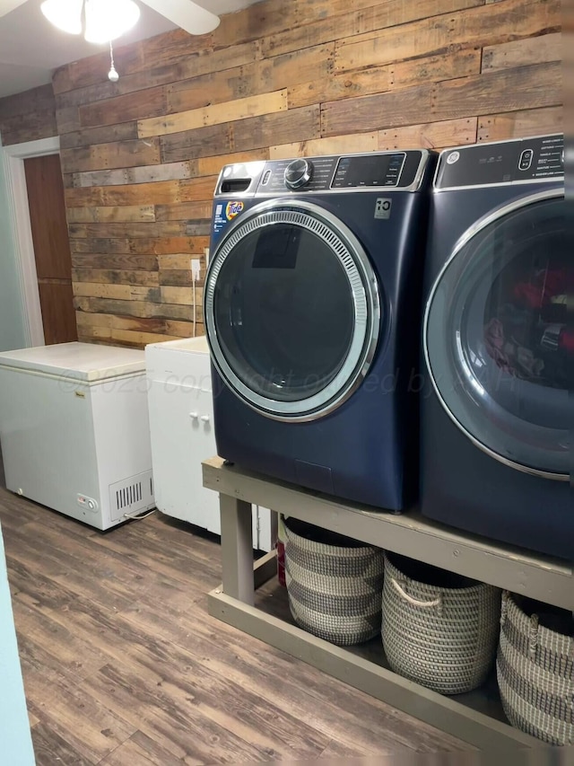 washroom with wooden walls, separate washer and dryer, laundry area, and wood finished floors