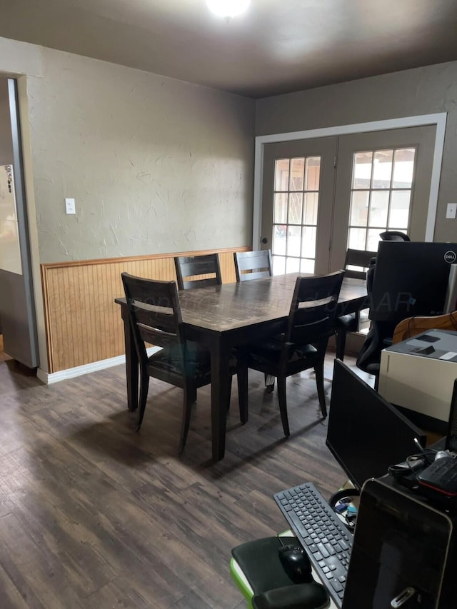 dining room with wood walls, a wainscoted wall, and dark wood finished floors