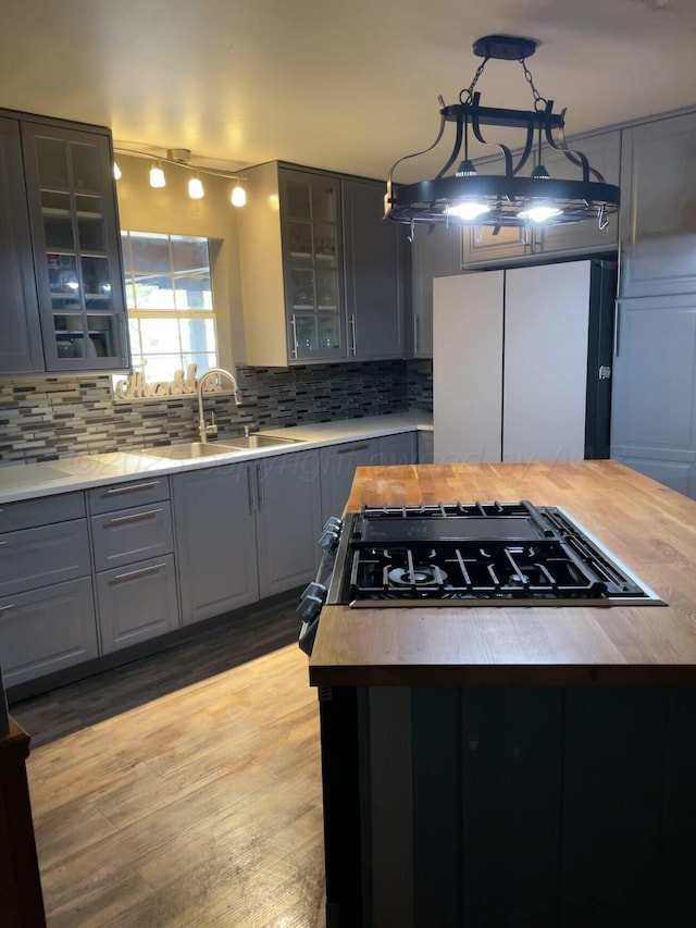 kitchen with a sink, light countertops, freestanding refrigerator, and gray cabinetry