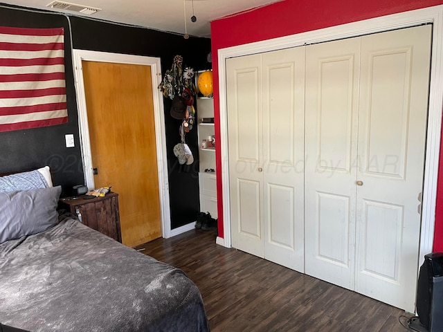 bedroom featuring a closet, dark wood-style flooring, and visible vents