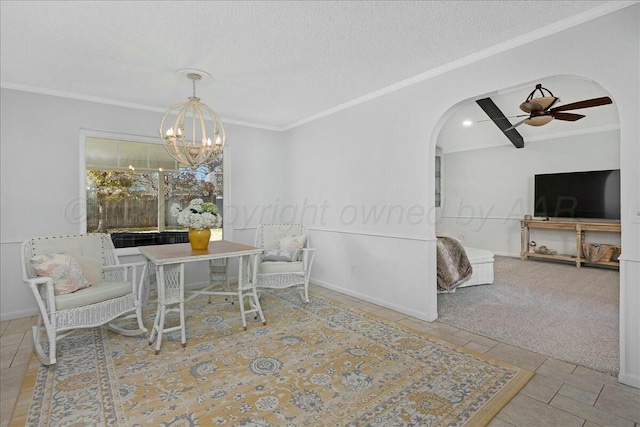 carpeted dining space with a textured ceiling, ceiling fan with notable chandelier, and ornamental molding