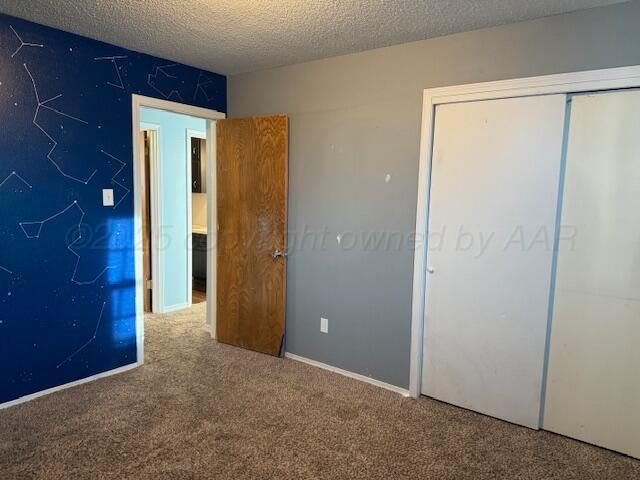 unfurnished bedroom with a closet, a textured ceiling, and carpet flooring