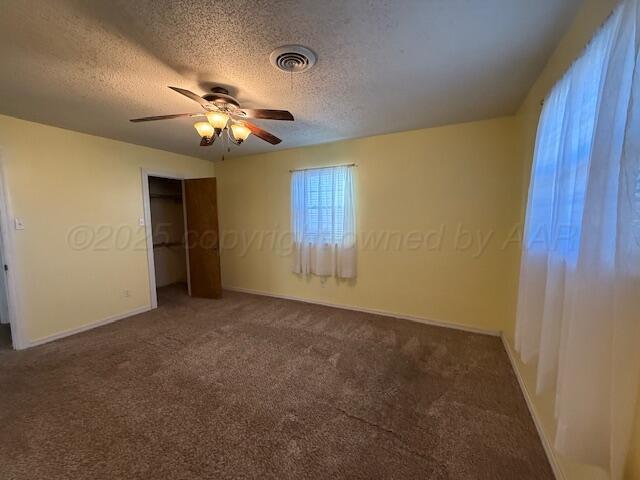 unfurnished bedroom featuring visible vents, a ceiling fan, a textured ceiling, a closet, and carpet