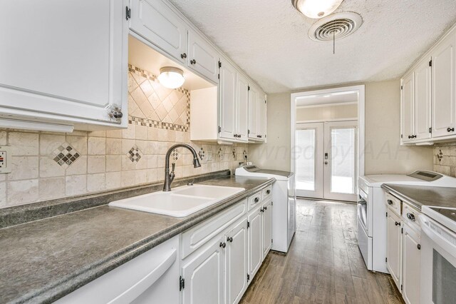 kitchen with white cabinetry, a sink, washing machine and dryer, french doors, and stove