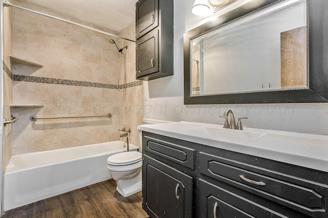 bathroom featuring a textured ceiling, toilet, wood finished floors, vanity, and shower / bathtub combination