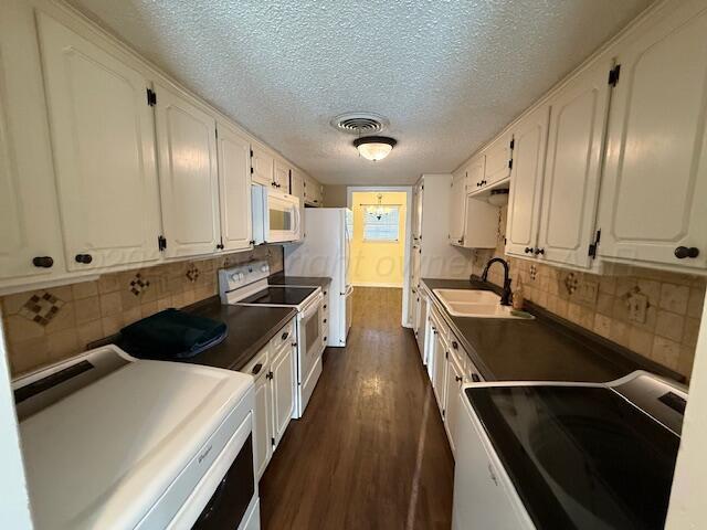 kitchen with visible vents, dark wood finished floors, white appliances, white cabinetry, and a sink