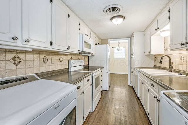 kitchen featuring white cabinets, visible vents, white appliances, washer / clothes dryer, and a sink
