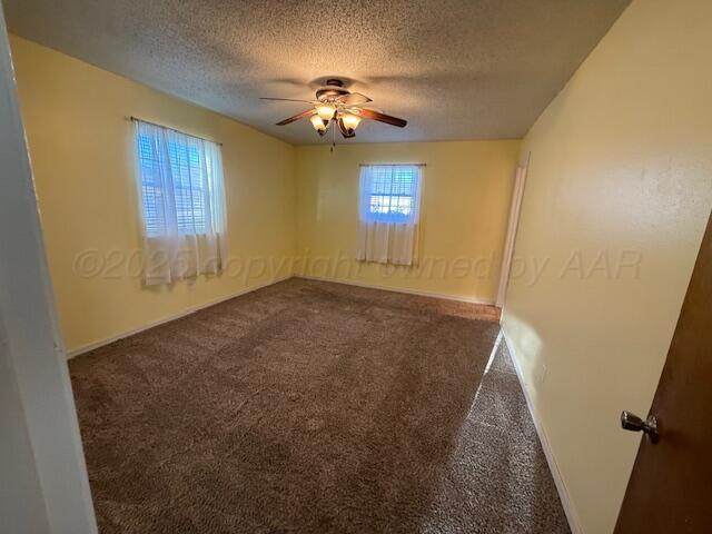 carpeted empty room with baseboards, a textured ceiling, and a ceiling fan