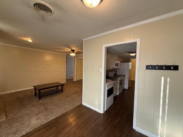 hall featuring visible vents, a textured ceiling, dark wood-style floors, crown molding, and baseboards