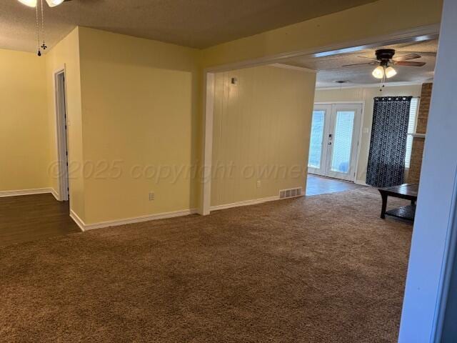 empty room featuring dark colored carpet, visible vents, and ceiling fan