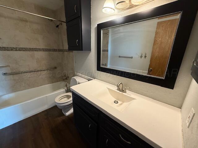 bathroom with toilet,  shower combination, wood finished floors, and vanity