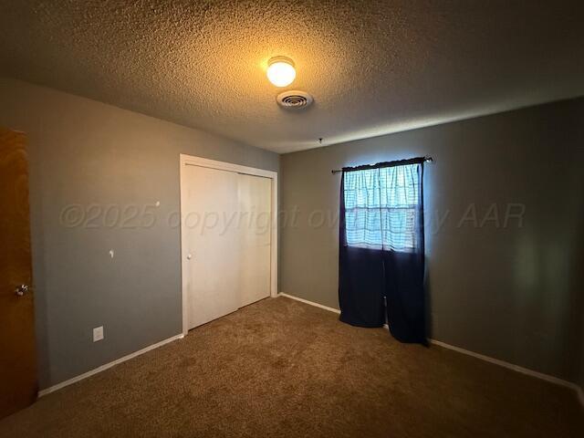 unfurnished bedroom with visible vents, baseboards, carpet flooring, a closet, and a textured ceiling