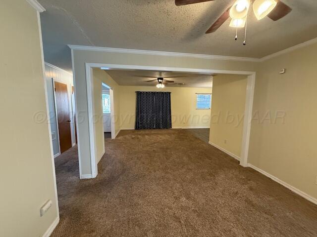 unfurnished room with baseboards, carpet floors, a textured ceiling, and ornamental molding