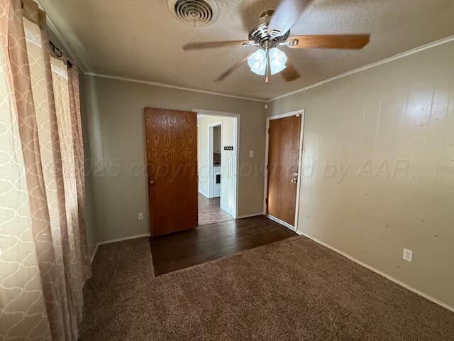 unfurnished bedroom with visible vents, a textured ceiling, ornamental molding, and carpet flooring