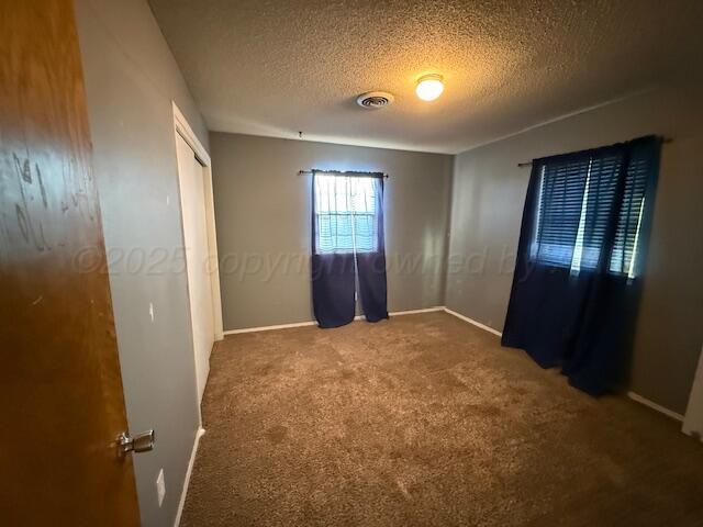 unfurnished bedroom with visible vents, carpet flooring, and a textured ceiling