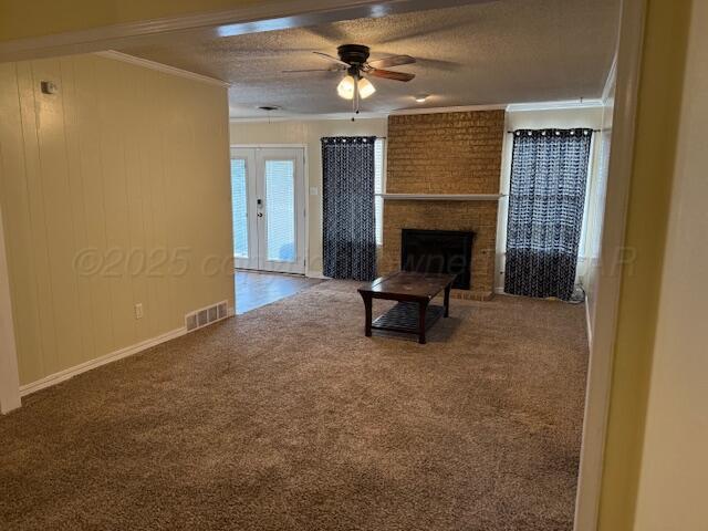 unfurnished living room featuring visible vents, a brick fireplace, crown molding, and carpet