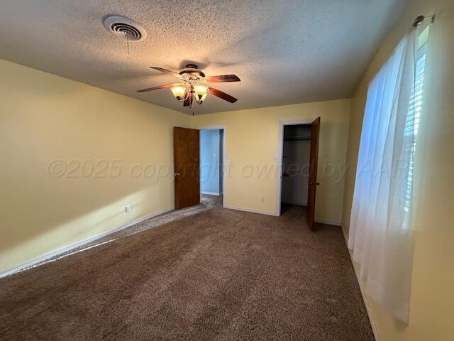 unfurnished bedroom with ceiling fan, carpet, visible vents, and a textured ceiling