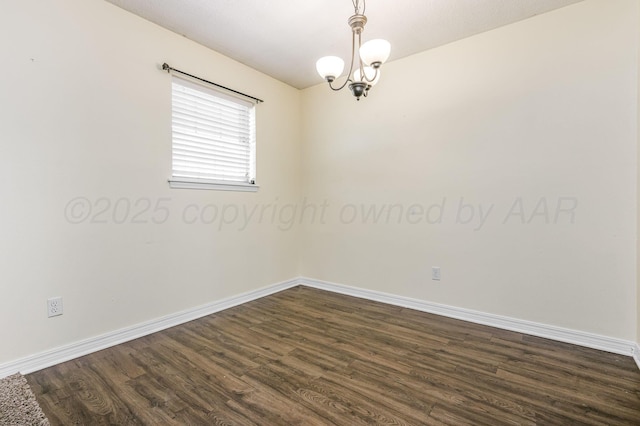 empty room featuring dark wood-type flooring, baseboards, and a chandelier