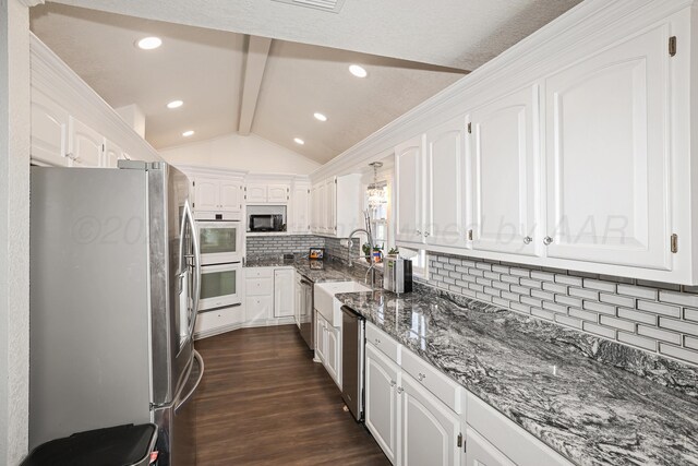 620 N Main St, Stratford, TX 79084 - kitchen with appliances with stainless steel finishes, a sink, white cabinetry, tasteful backsplash, and dark wood-style flooring